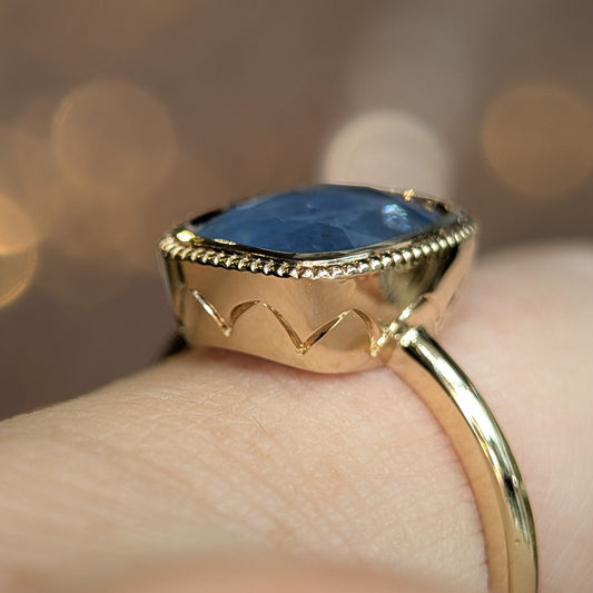 Gold ring with a blue gemstone on a blurred background