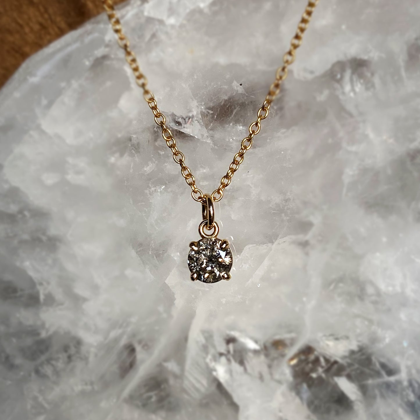 A sparkly and ethereal medium grey salt and pepper diamond in a dainty claw setting.