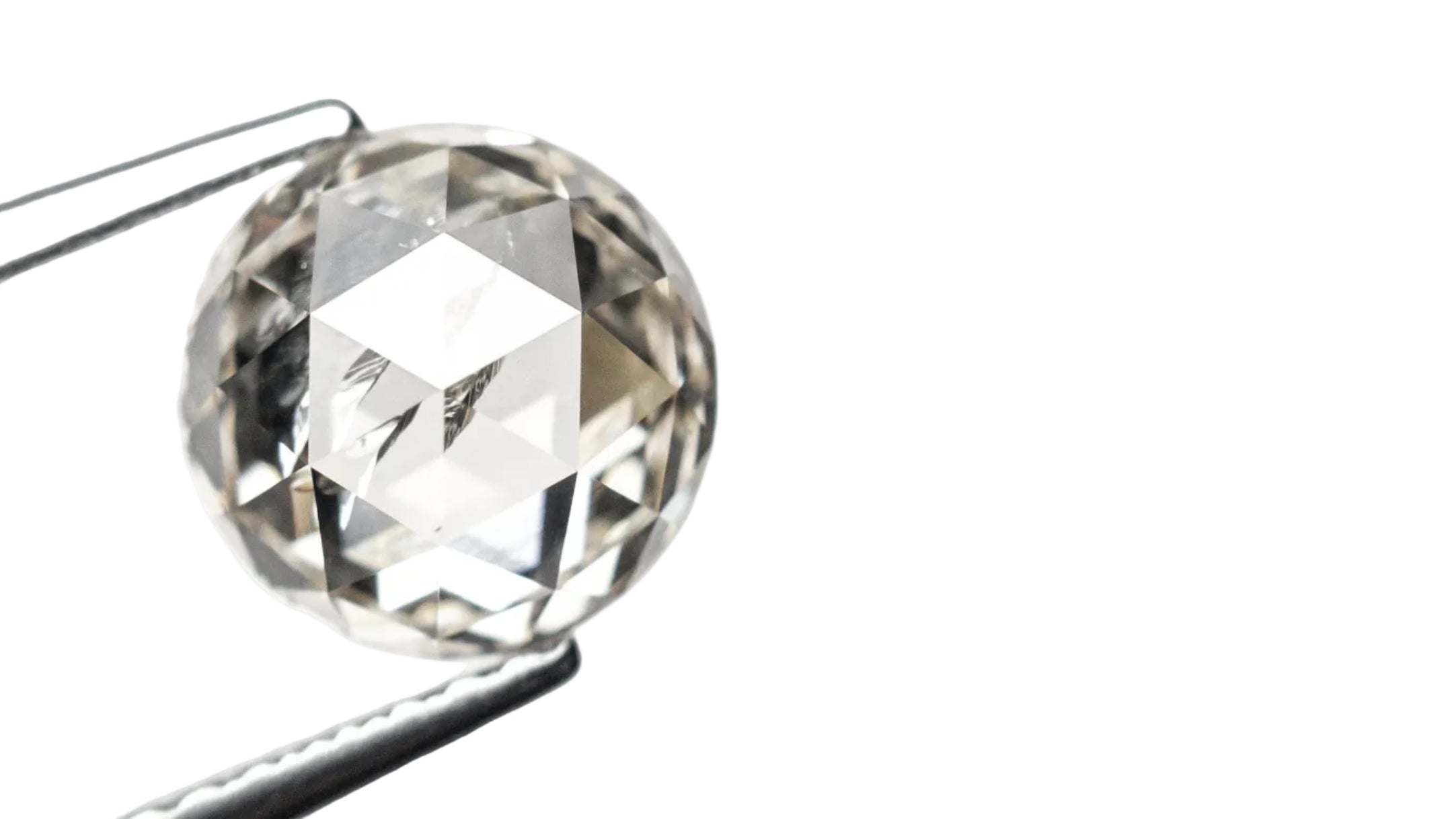 Clear diamond held by tweezers on a white background