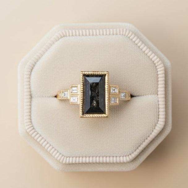 Gold ring with a black gemstone on a gray cushion