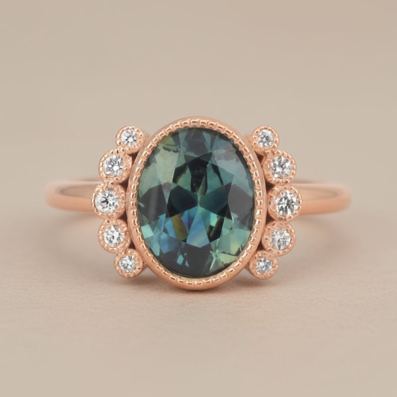 Rose gold ring with a teal sapphire and small diamonds 