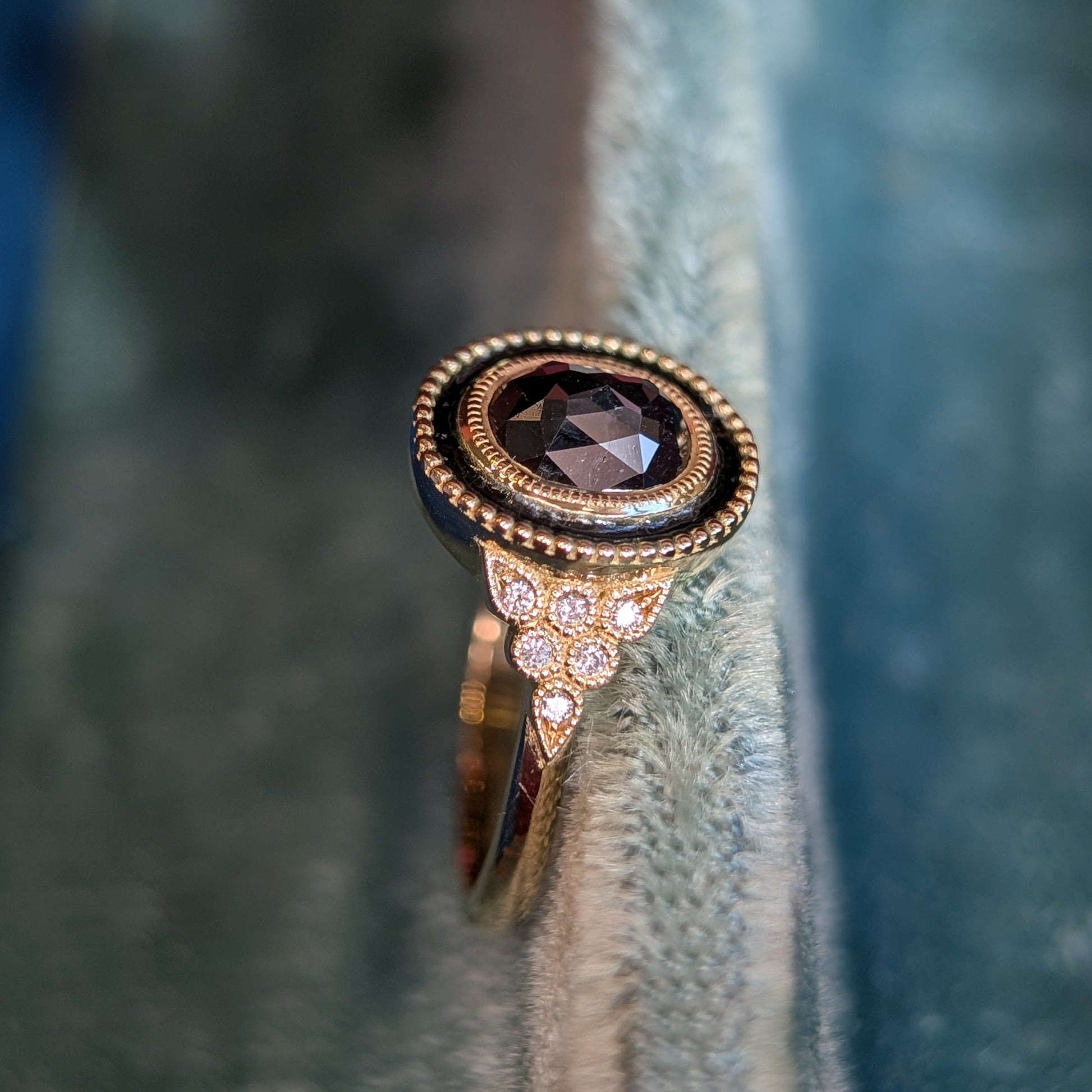 Yellow gold ring with a black diamond on a textured fabric background