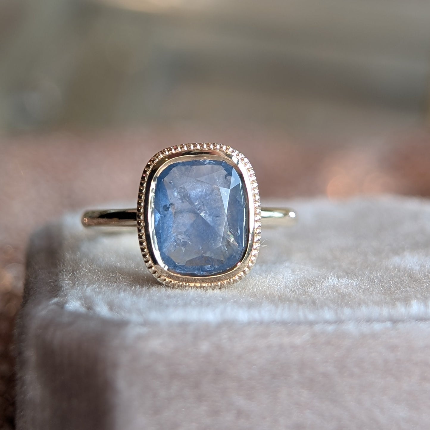Ring with a blue gemstone and gold band on a soft surface