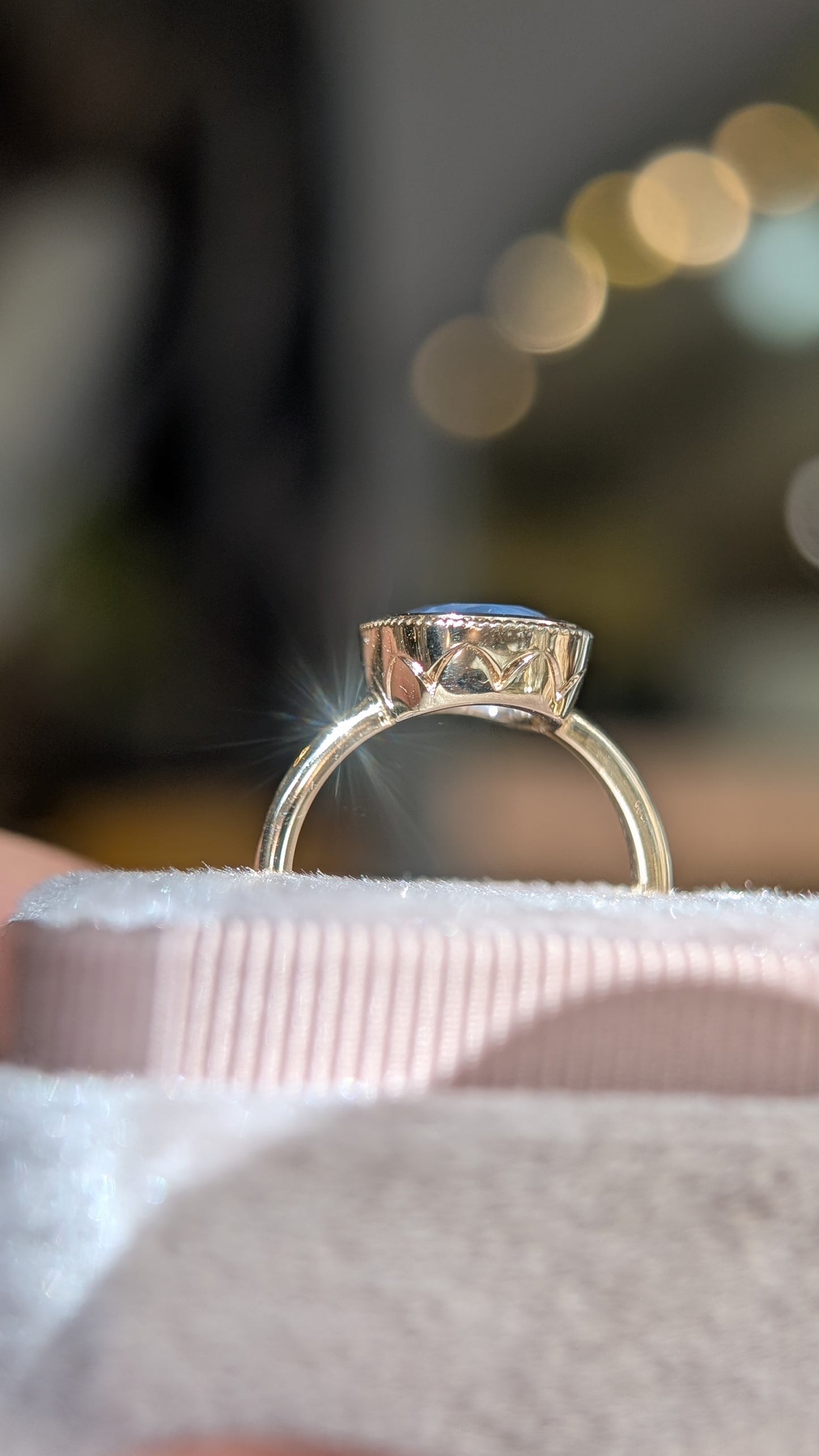 Gold ring with a blue stone on a white surface with a blurred background
