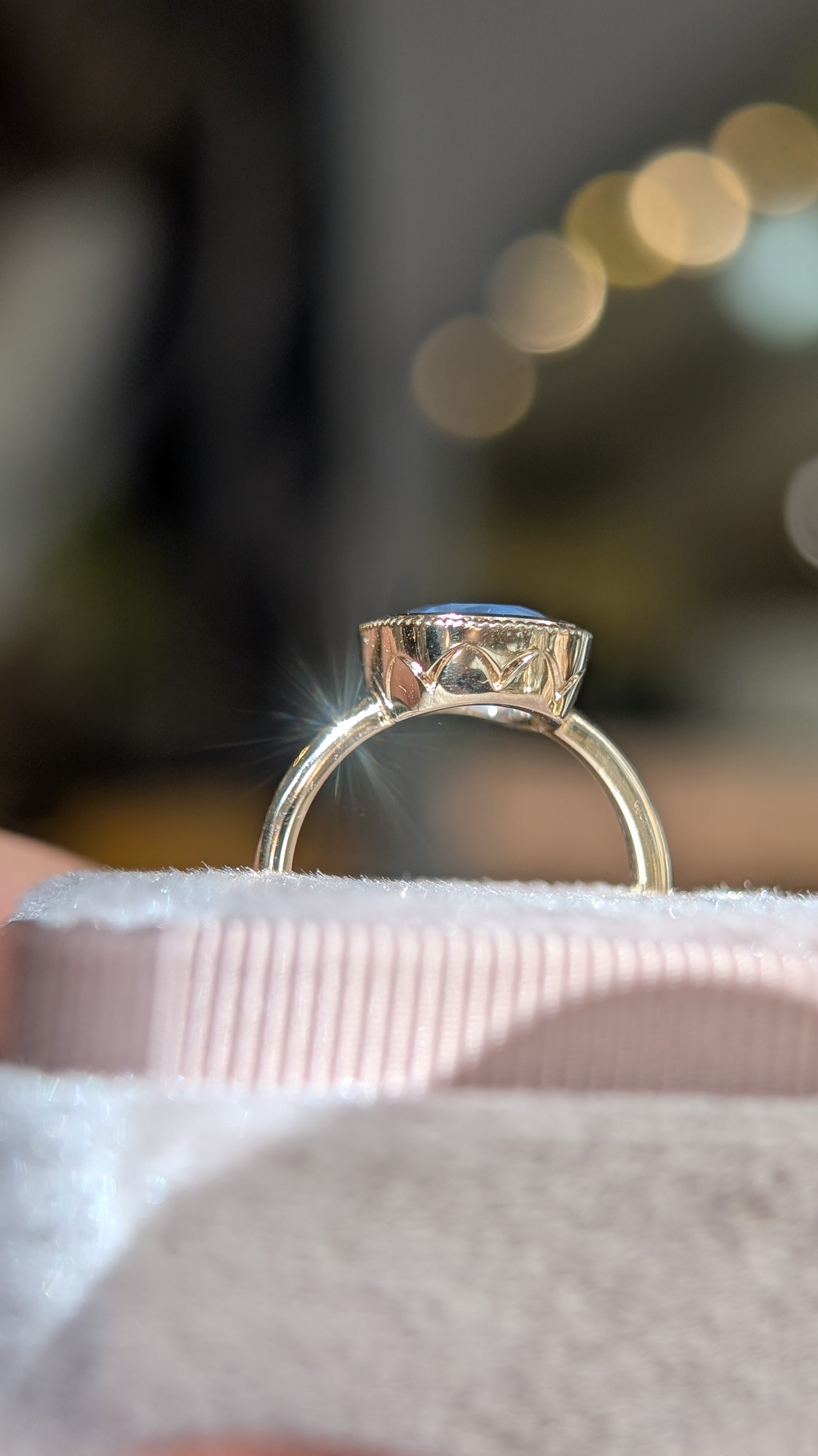 Gold ring with a blue stone on a white surface with a blurred background