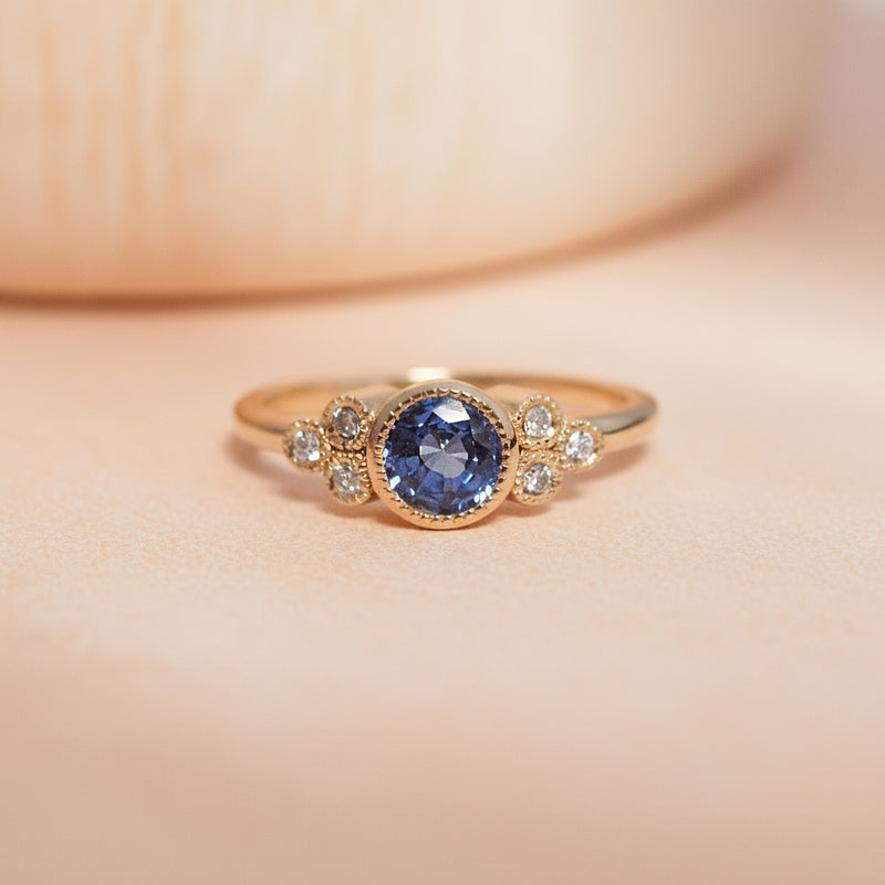Gold ring with a blue gemstone on a light gray background
