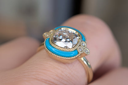 Gold ring with a large diamond and turquoise stone on a finger