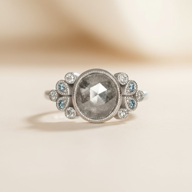 white gold ring with a large central diamond stone and smaller stones on a white background
