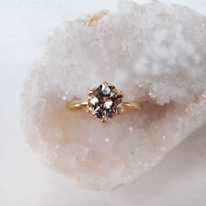 Gold ring with a brown  diamond on a textured white surface