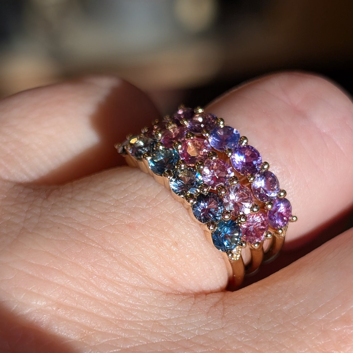 Multicolored gemstone ring on a finger with a blurred background
