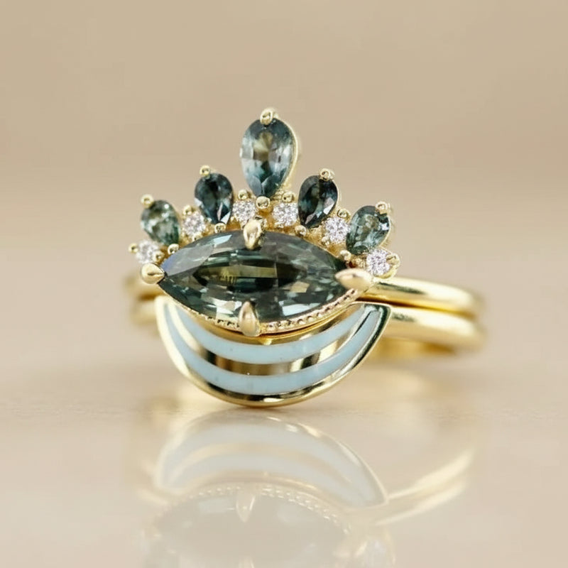 Gold ring with green gemstones on a reflective surface