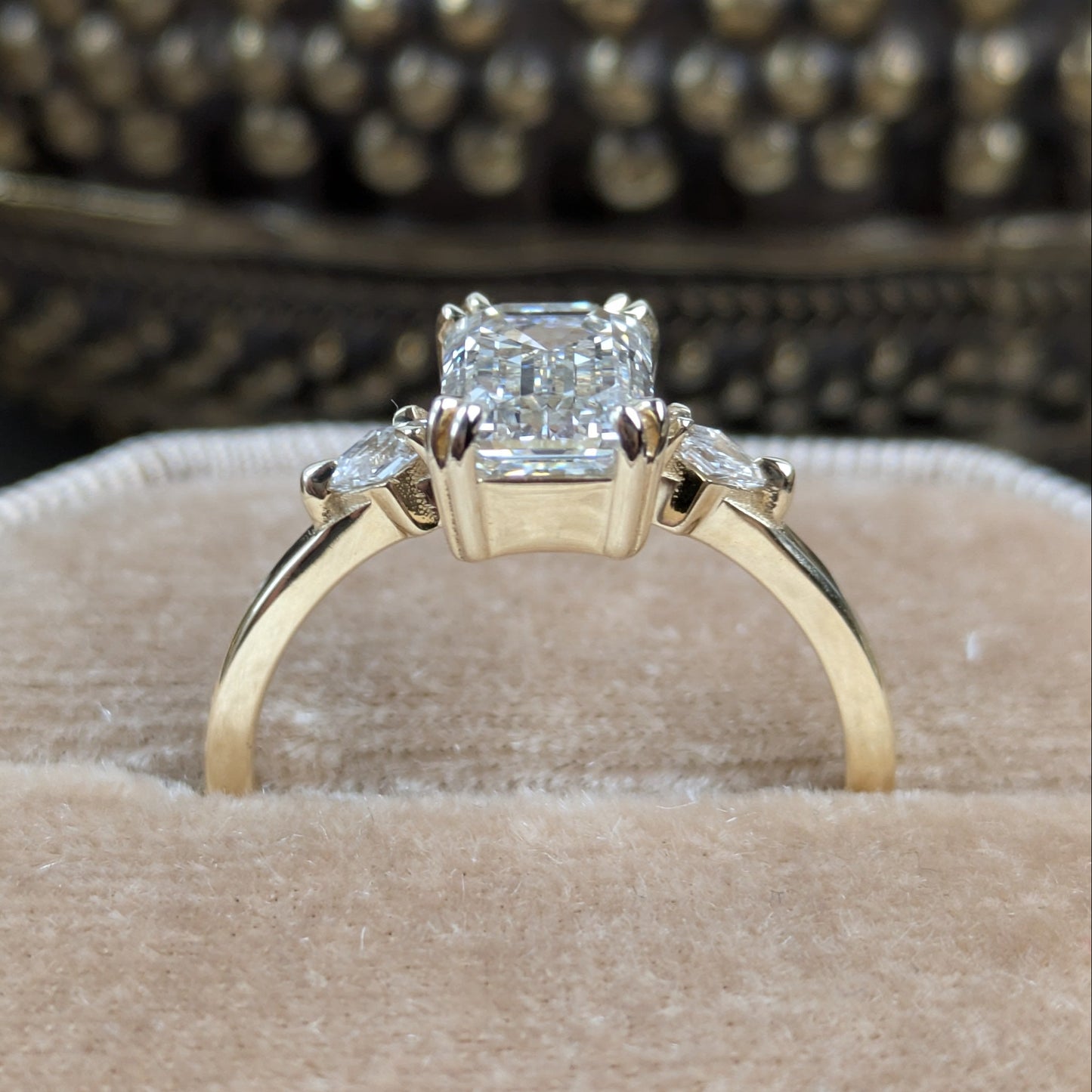 Gold ring with a diamond on a beige cushion