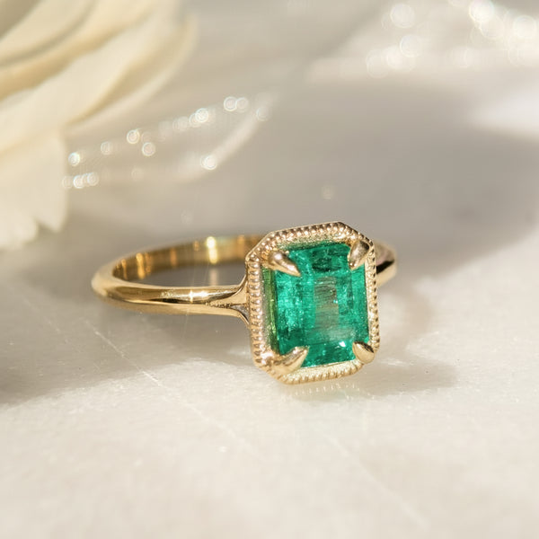 18k yellow Gold ring with a green emerald gemstone on a white surface