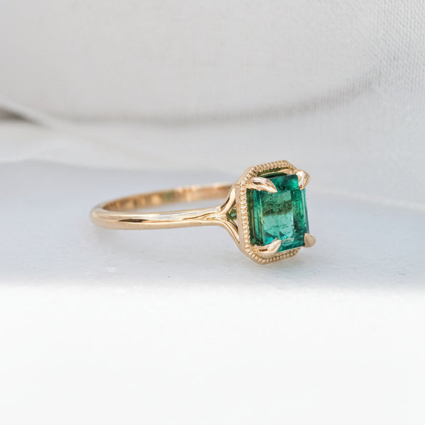 Gold ring with a green gemstone on a white background