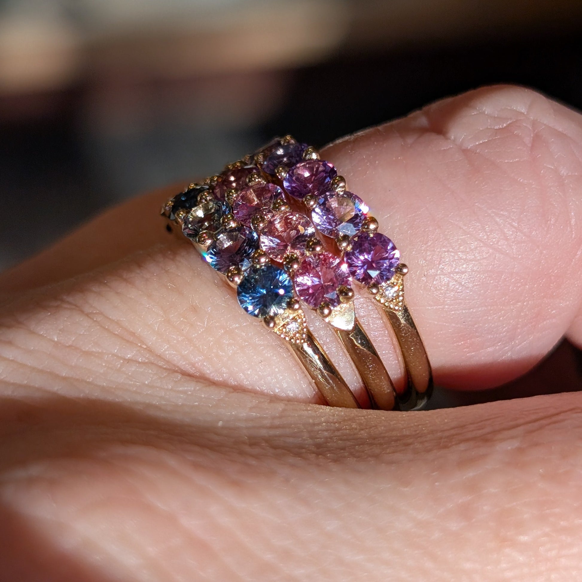 Multicolored gemstone ring on a finger with a blurred background