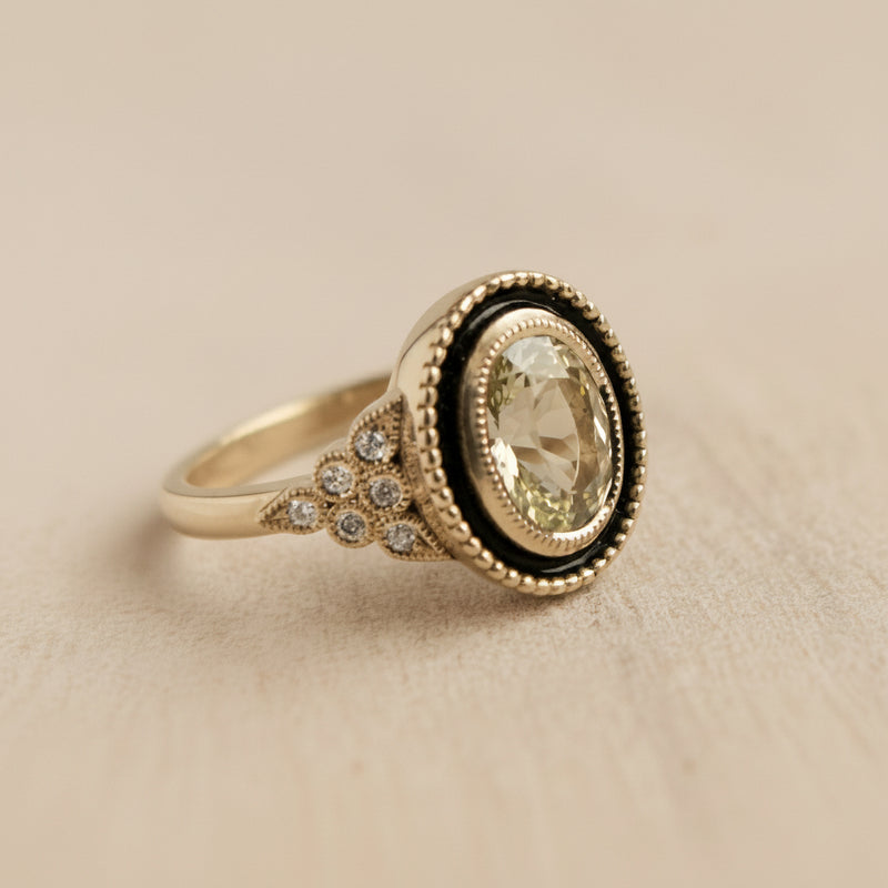 Gold ring with a large gemstone and smaller diamonds on a light gray background