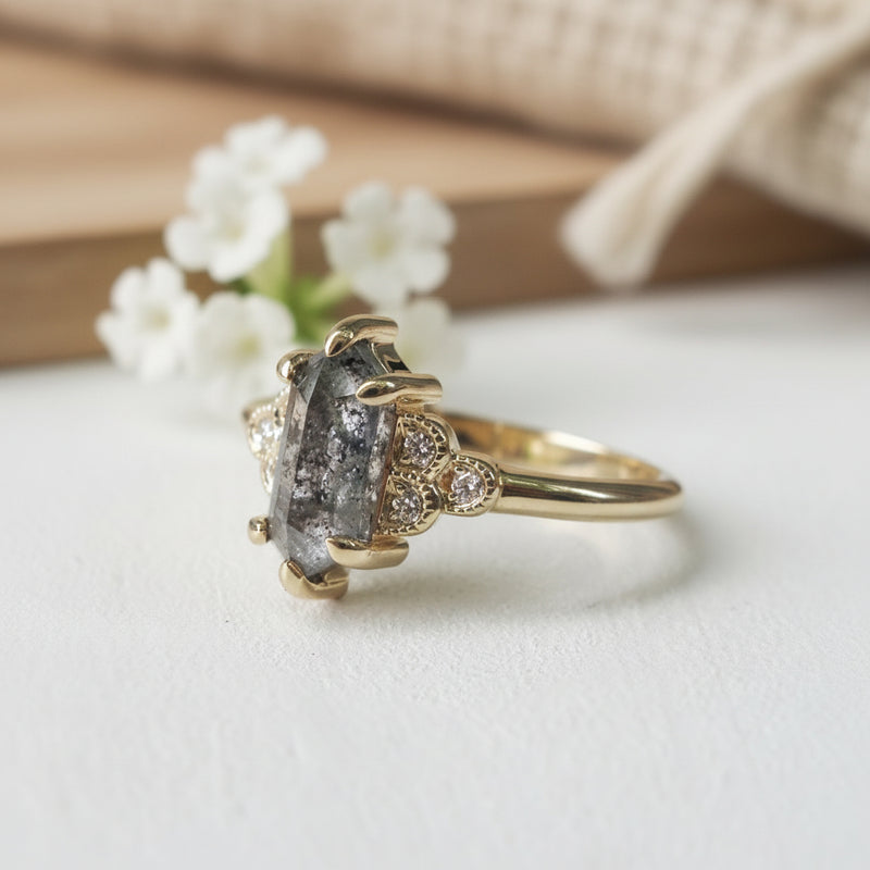 Gold ring with a central gemstone and smaller stones on a white background