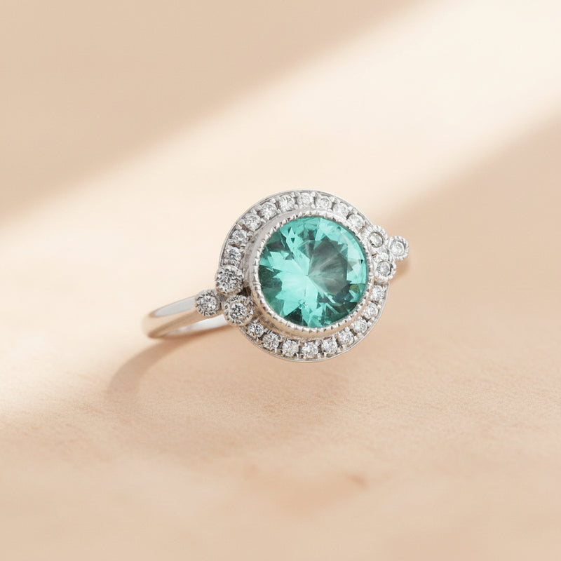 Silver ring with a green gemstone on a white stone background