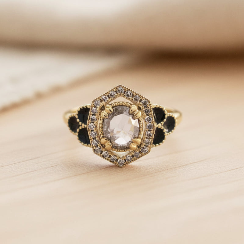Gold ring with black accents and a central gemstone on a white background