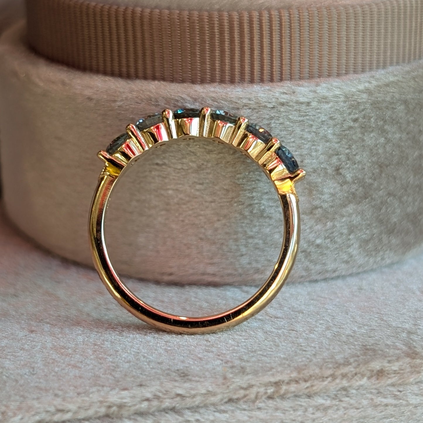 Gold ring with embedded stones on a textured surface