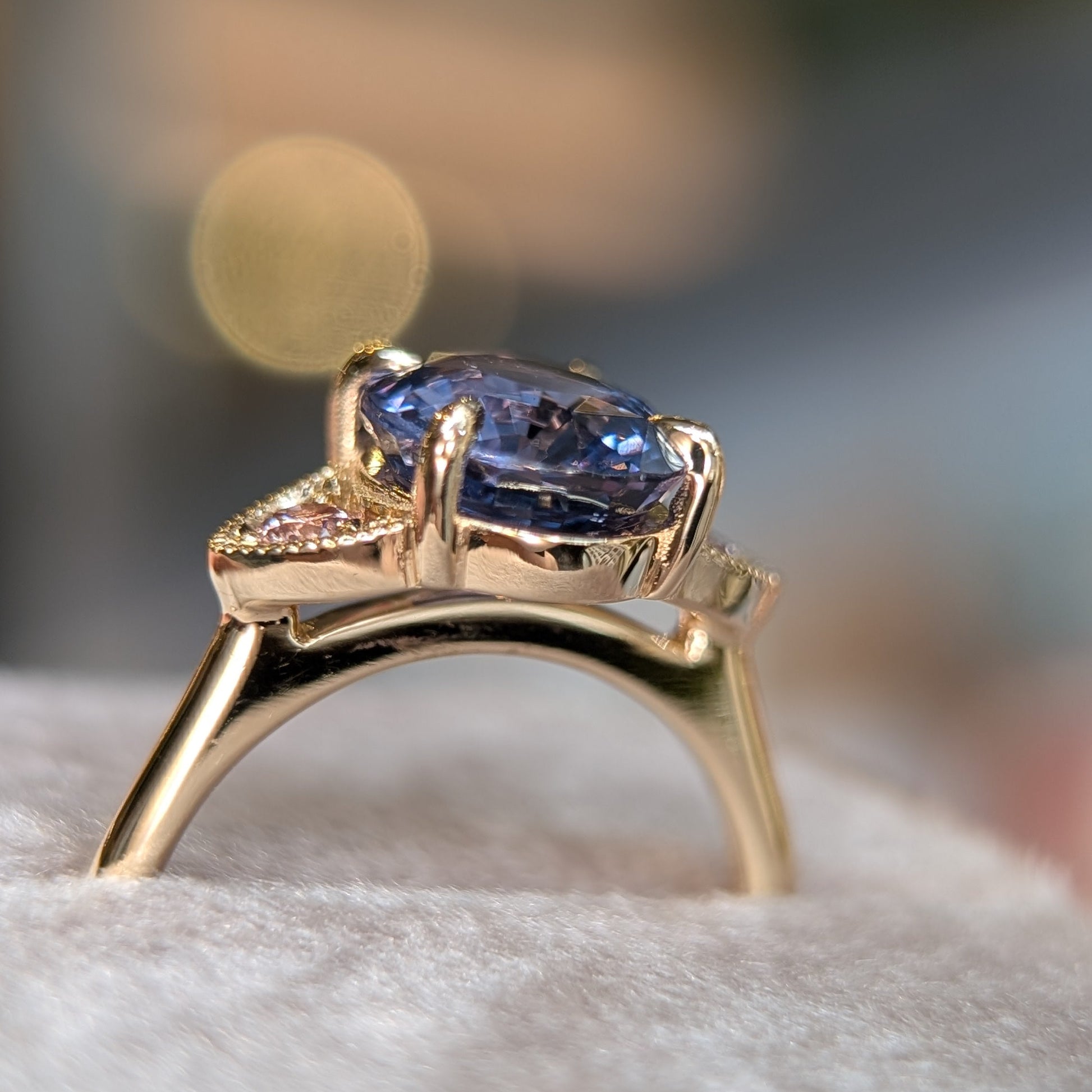 Gold ring with a purple gemstone on a soft surface