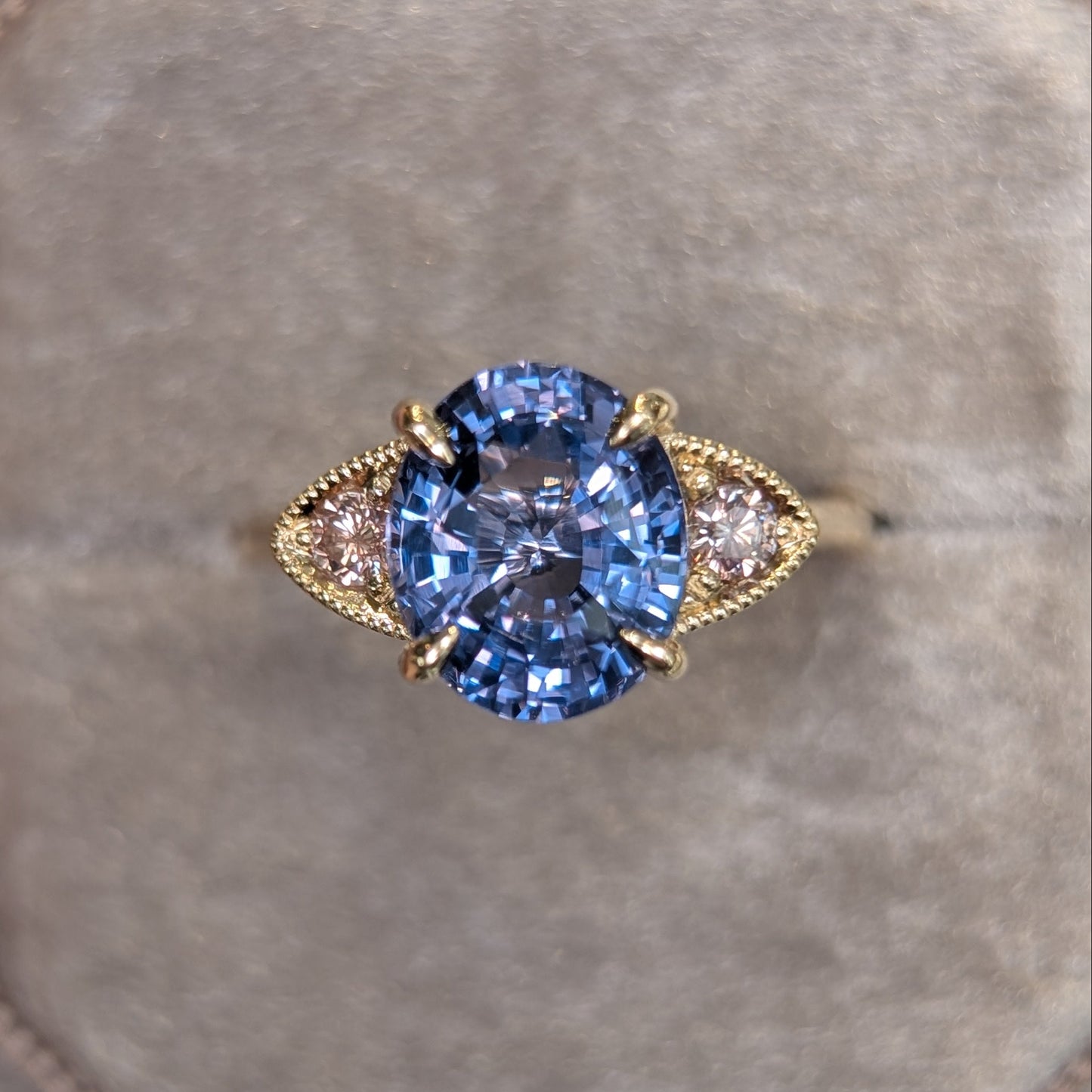 Gold ring with a purple gemstone on a gray cushion