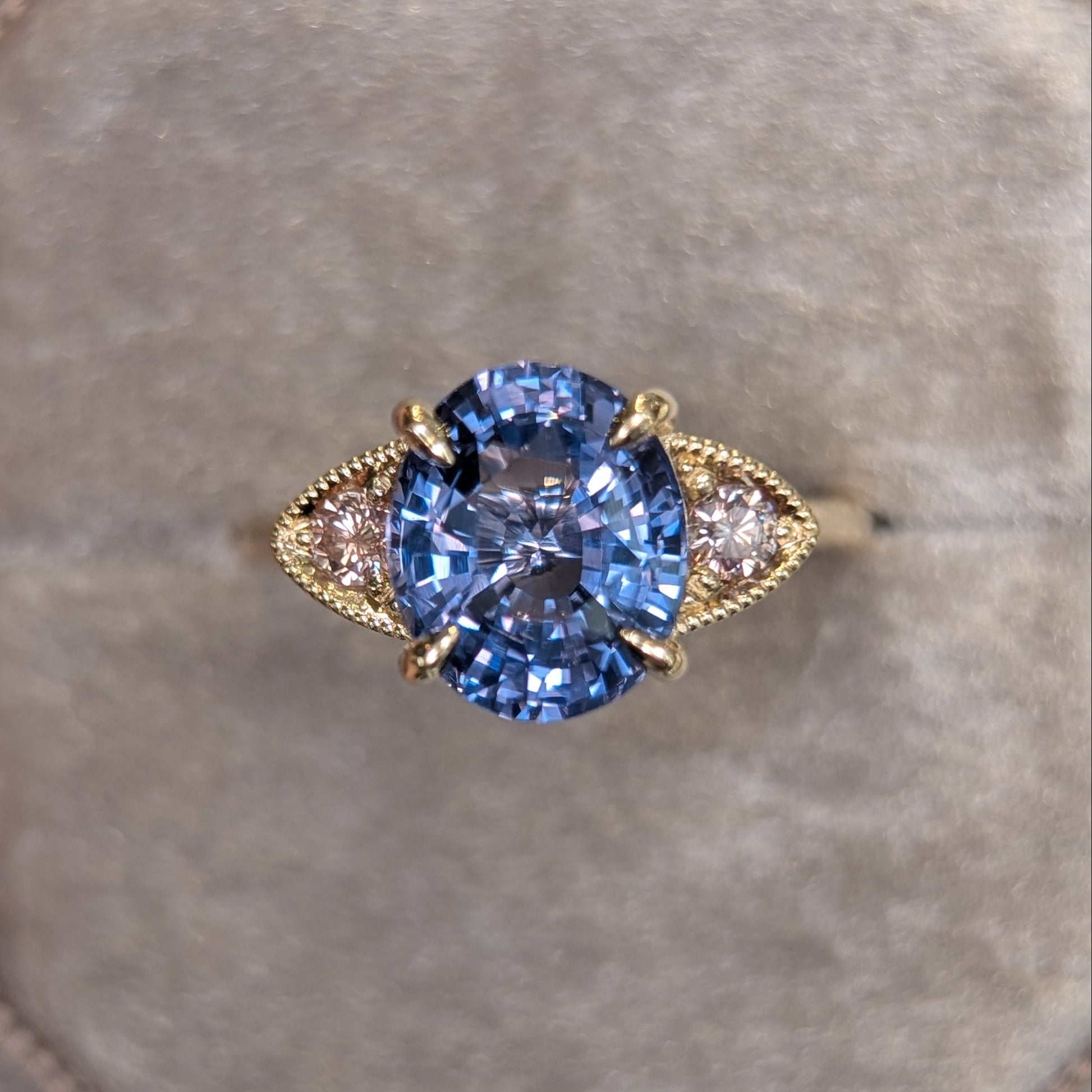 Gold ring with a purple gemstone on a gray cushion