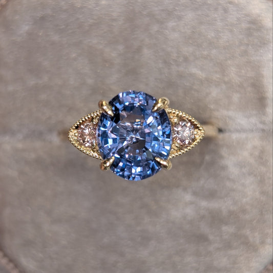 Gold ring with a purple gemstone on a gray cushion