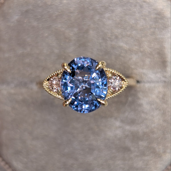 Gold ring with a purple gemstone on a gray cushion