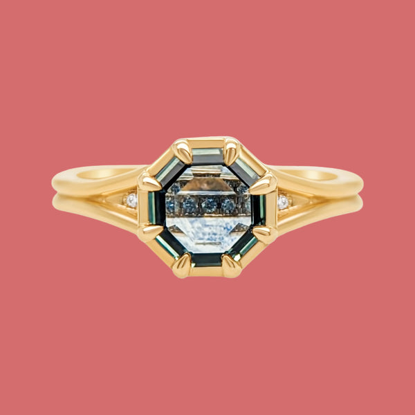 A 14K yellow gold engagement ring with a split shank design and a central Montana sapphire, surrounded by small diamond accents.