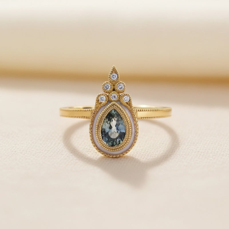 Gold ring with a teardrop-shaped gemstone on a white background