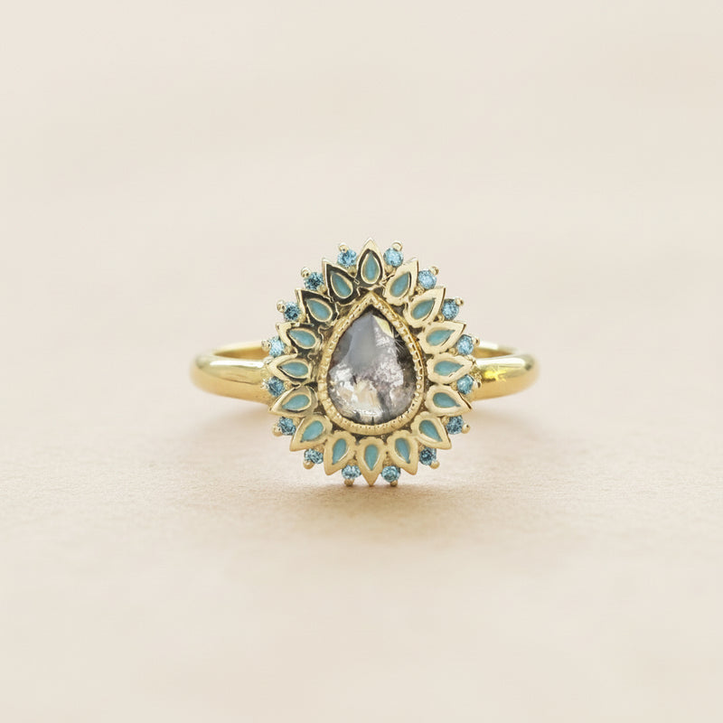 Gold ring with a central gemstone and turquoise accents on a white background