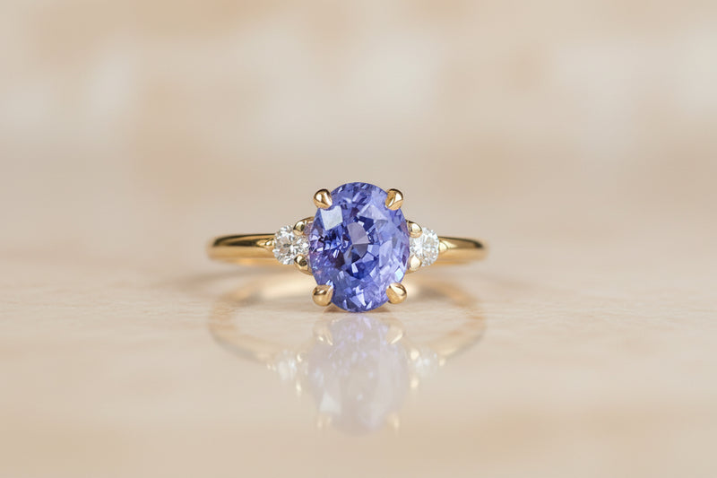 Gold ring with a purple gemstone on a beige background