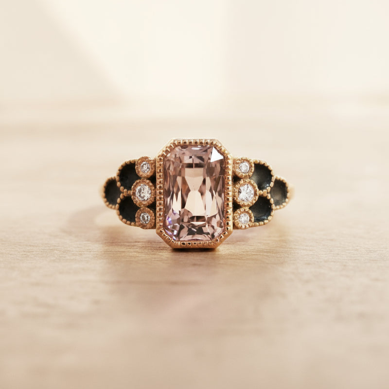 Elegant ring with a pink gemstone and black accents on a white background