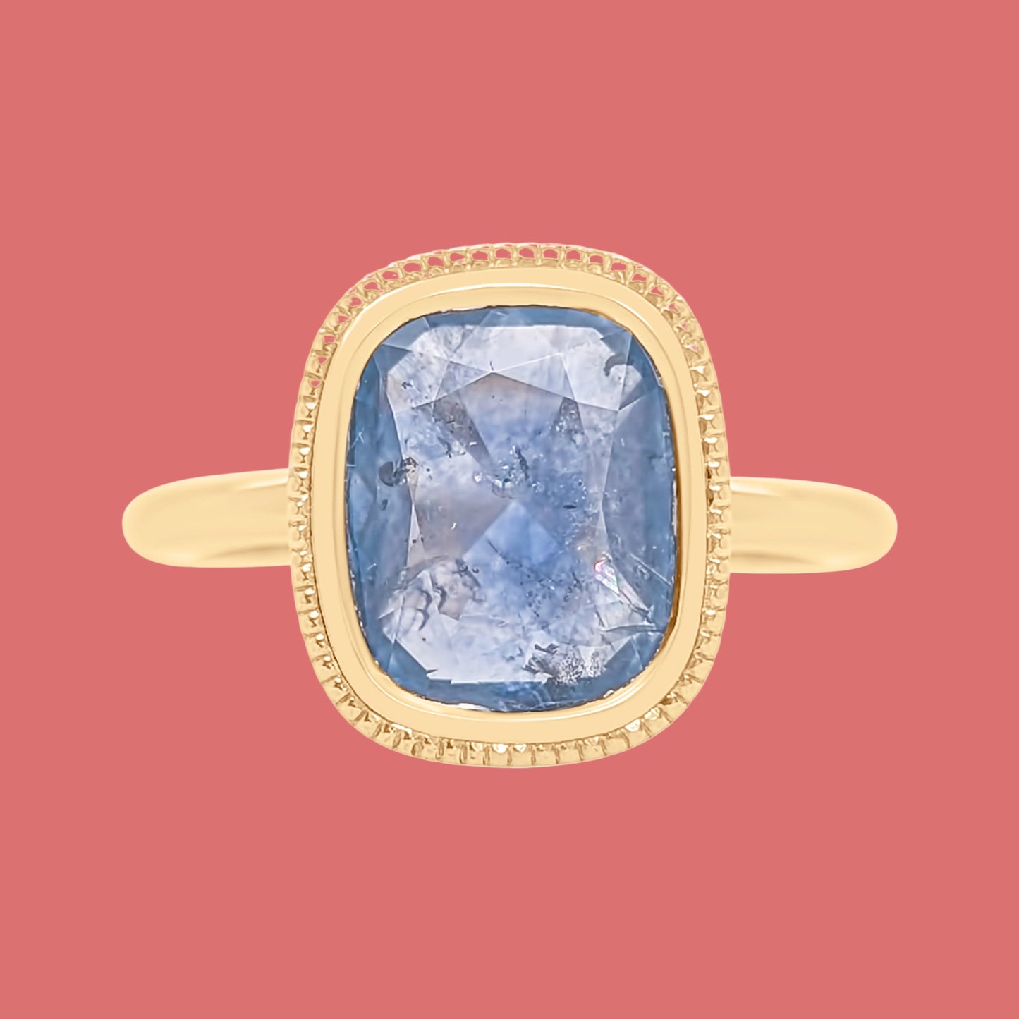 Gold ring with a blue gemstone on a white background