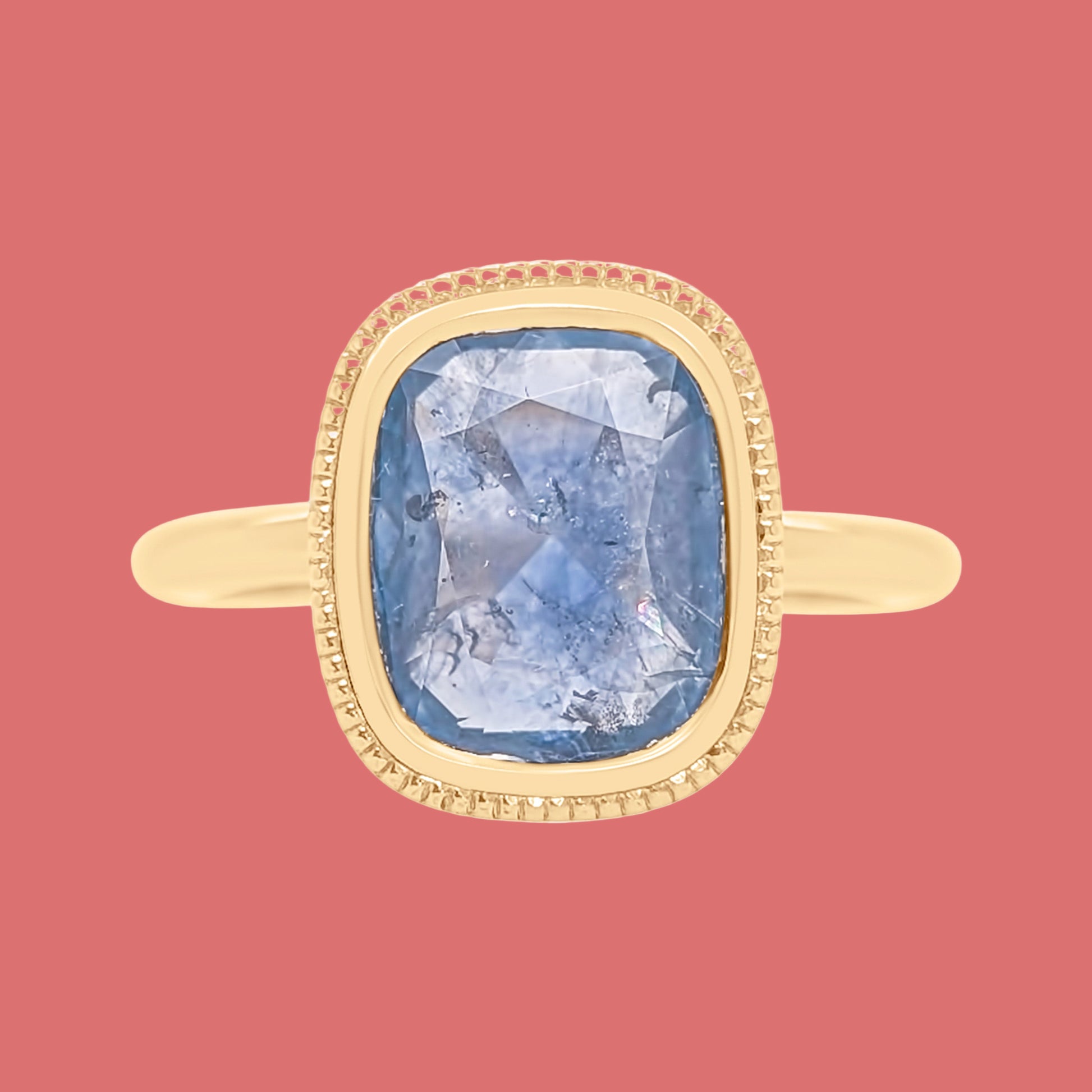 Gold ring with a blue gemstone on a white background