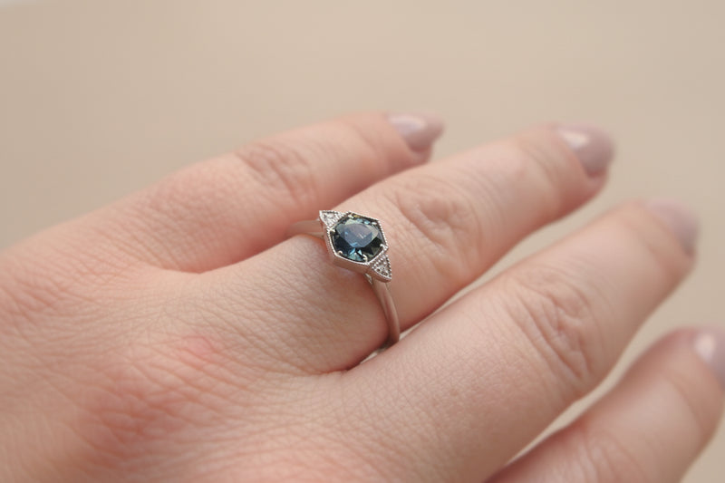 platinum ring with a blue gemstone on a person's finger