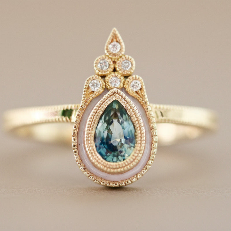 Gold ring with a teardrop-shaped gemstone on a light background