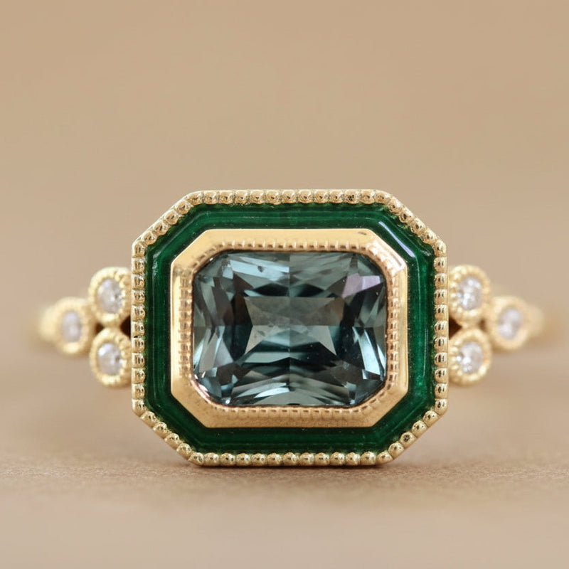 Gold ring with a green gemstone on a light background