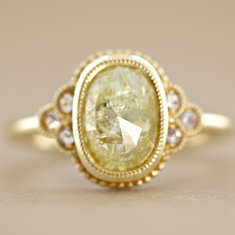 Gold ring with a yellow diamond and pearl accents on a light gray background