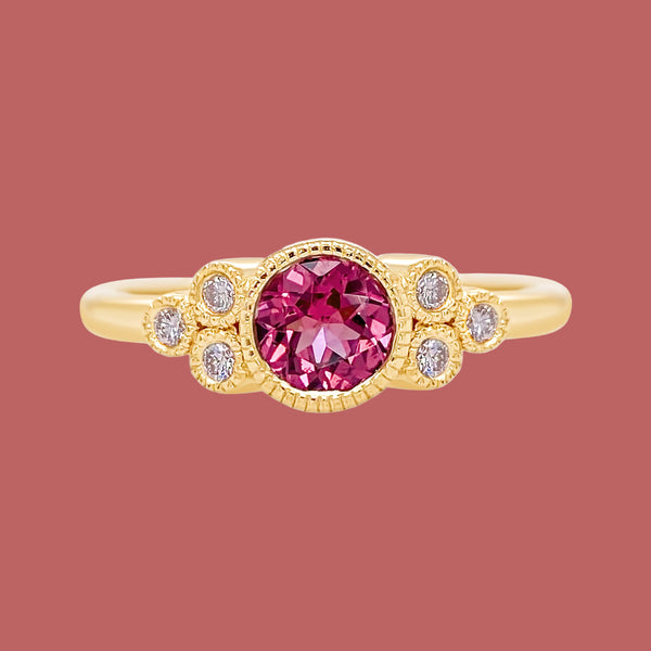 Gold ring with a pink gemstone and smaller diamonds on a white background