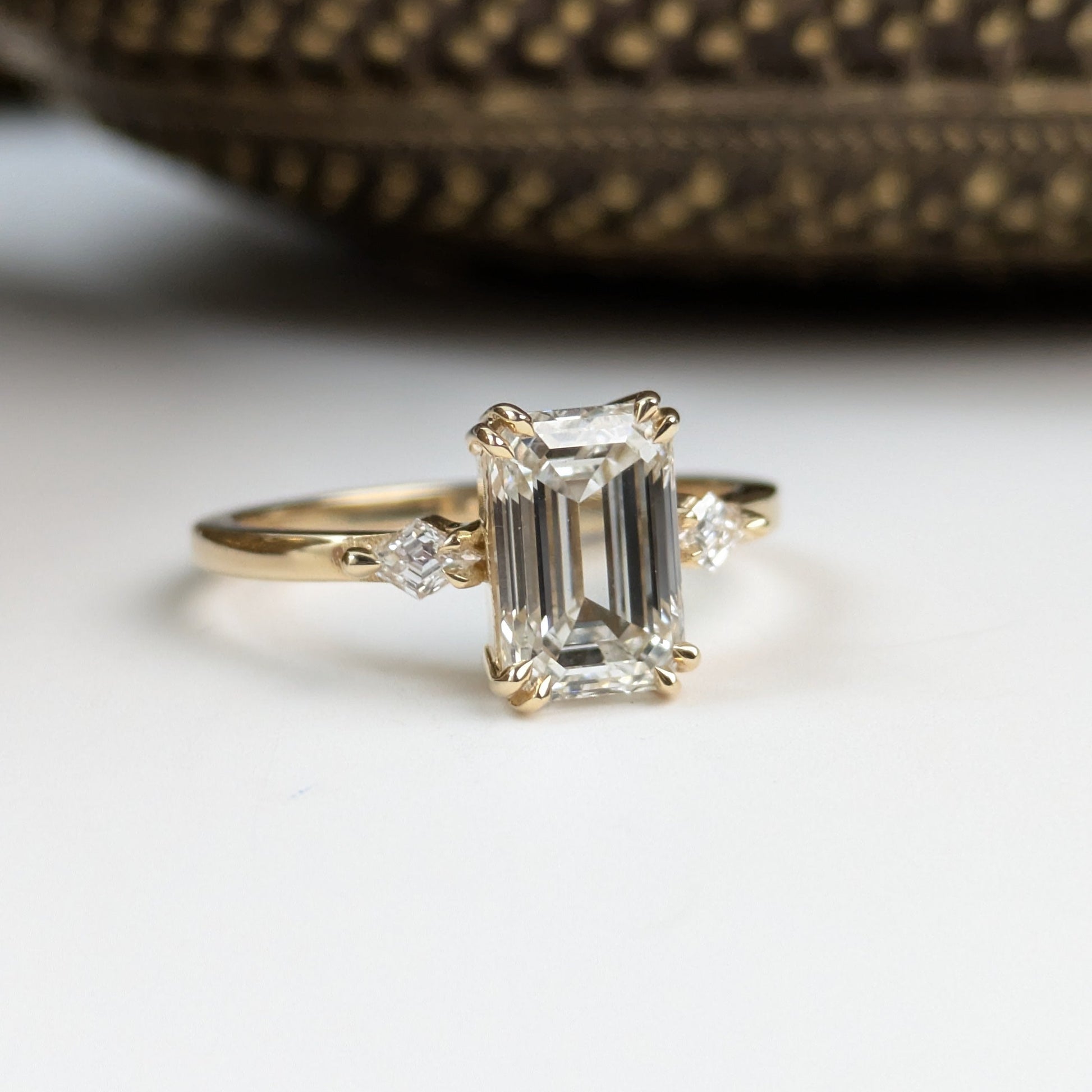 Gold ring with emerald-cut diamond on a white surface