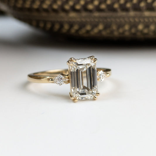 Gold ring with emerald-cut diamond on a white surface