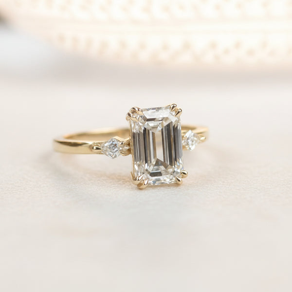 Gold ring with emerald-cut diamond on a white surface