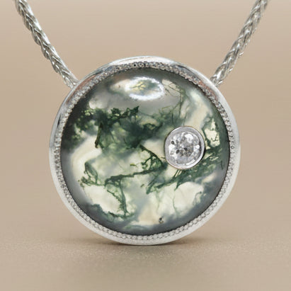 Necklace with a pendant featuring a green marbled moss agate and a diamond on a white background