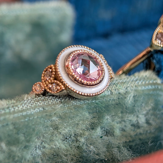 Close-up of a decorative ring with a pink gemstone on a textured surface.