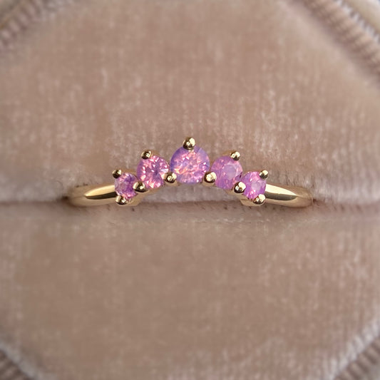 Gold ring with pink gemstones on a beige background