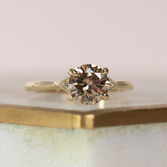 Gold ring with a diamond on a light pink surface