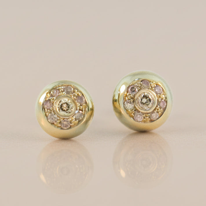 Pair of gold earrings with gemstones on a beige background