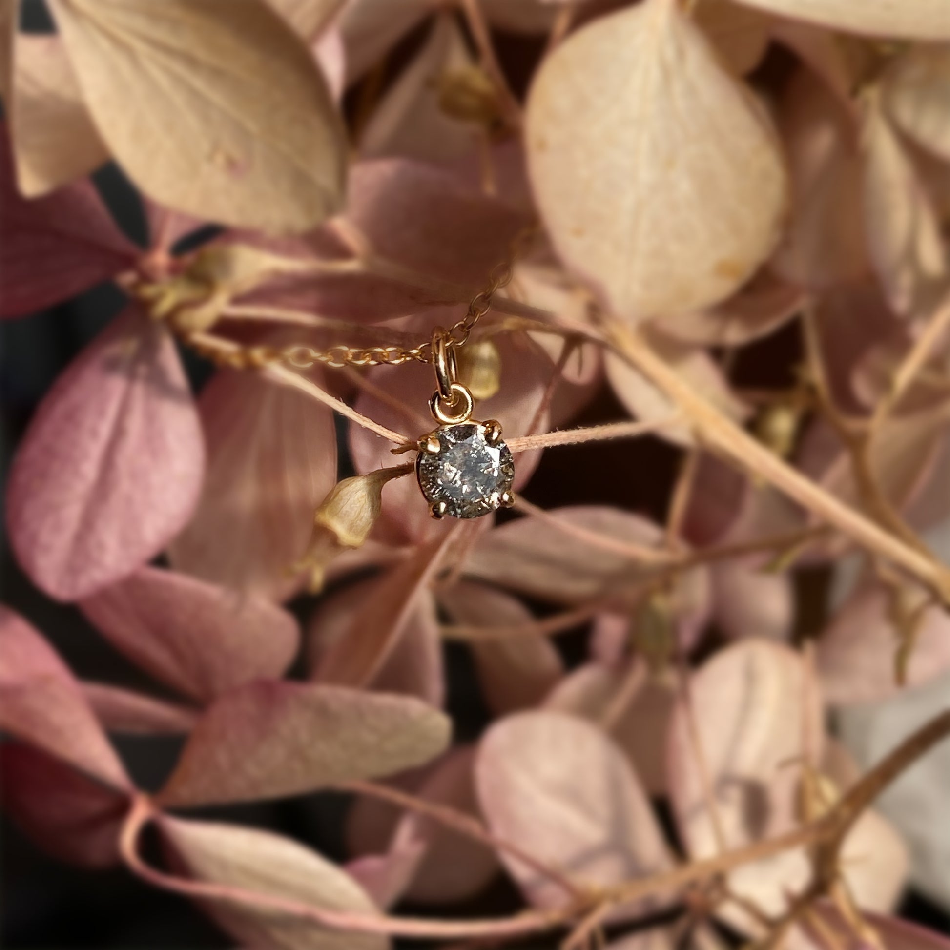 A sparkly and ethereal medium grey salt and pepper diamond in a dainty claw setting. 